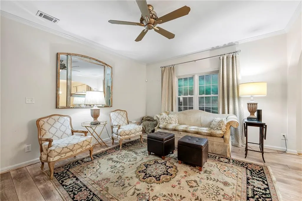 Living room featuring ceiling fan, crown molding, and light hardwood / wood-style floors