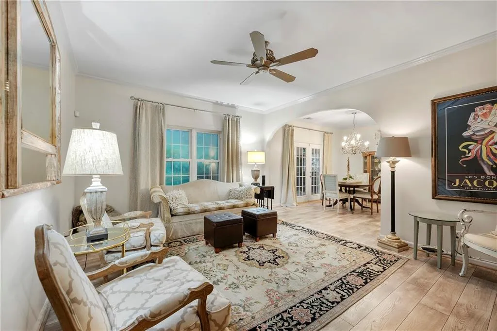 Living room with light hardwood / wood-style flooring, ceiling fan with notable chandelier, and crown molding
