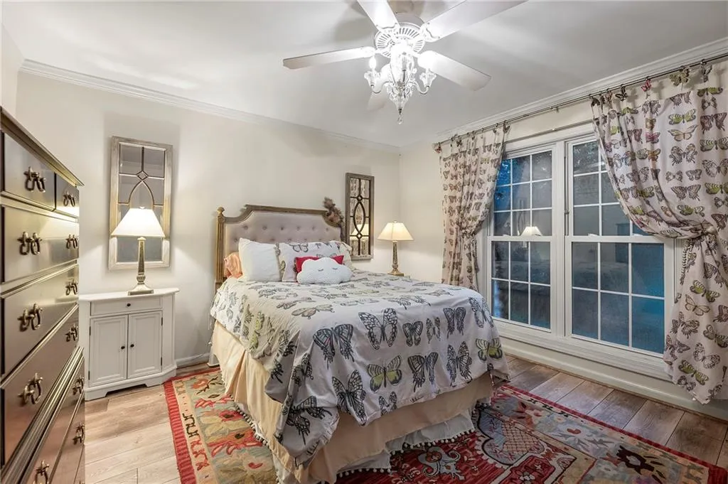 Bedroom with light wood-type flooring, ceiling fan, and crown molding, large closet