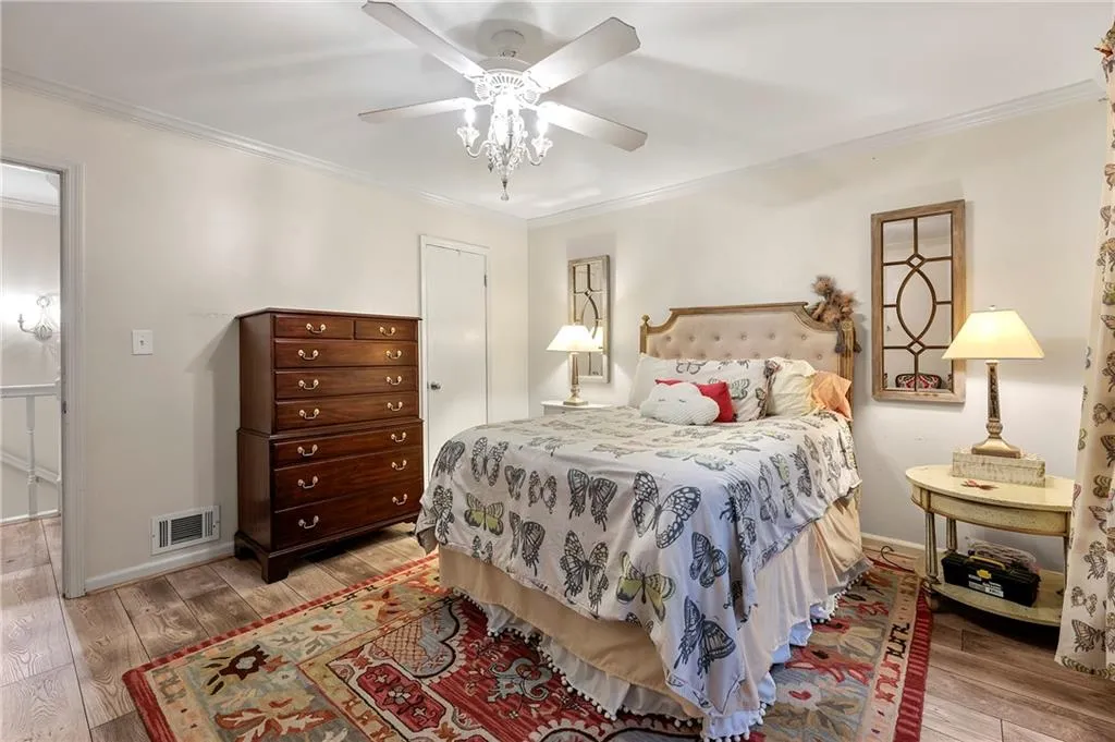 Bedroom with ceiling fan, crown molding, and light hardwood / wood-style floors