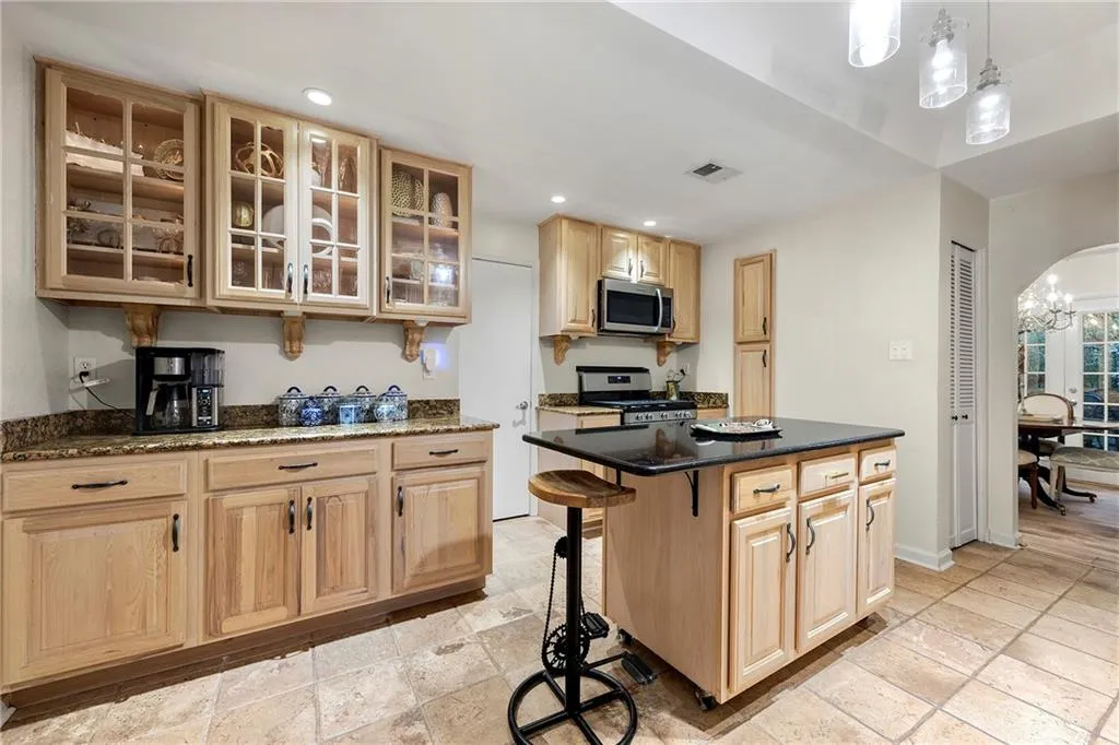 Kitchen featuring a center island, a notable chandelier, hanging light fixtures, light brown cabinets, and appliances with stainless steel finishes