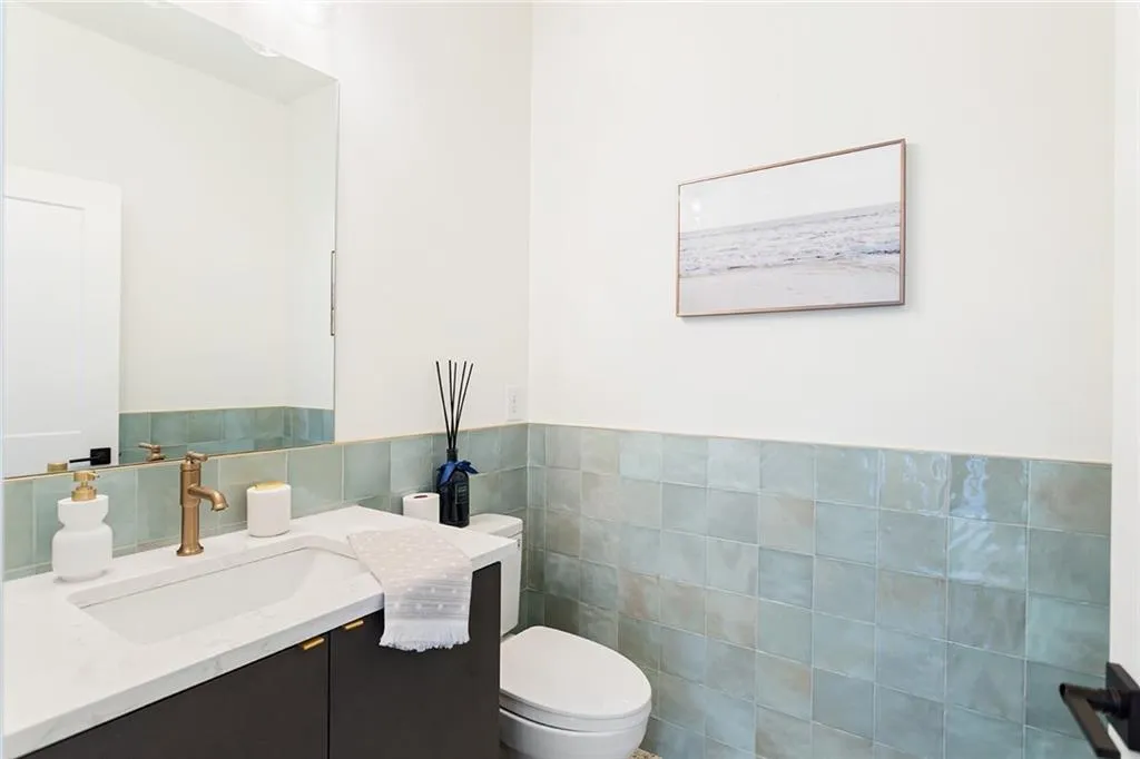 Half bath with tile walls, vanity, and wainscoting