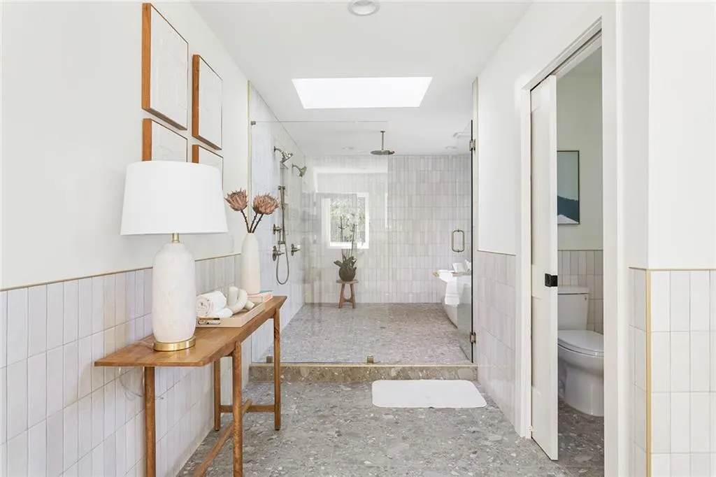 Hall featuring a wainscoted wall, tile walls, and a skylight