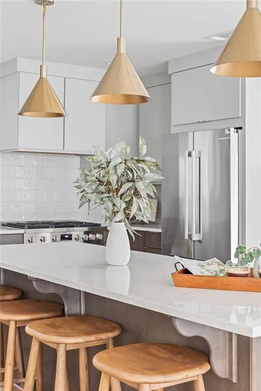 Kitchen with backsplash, light stone counters, a kitchen bar, freestanding refrigerator, and modern cabinets