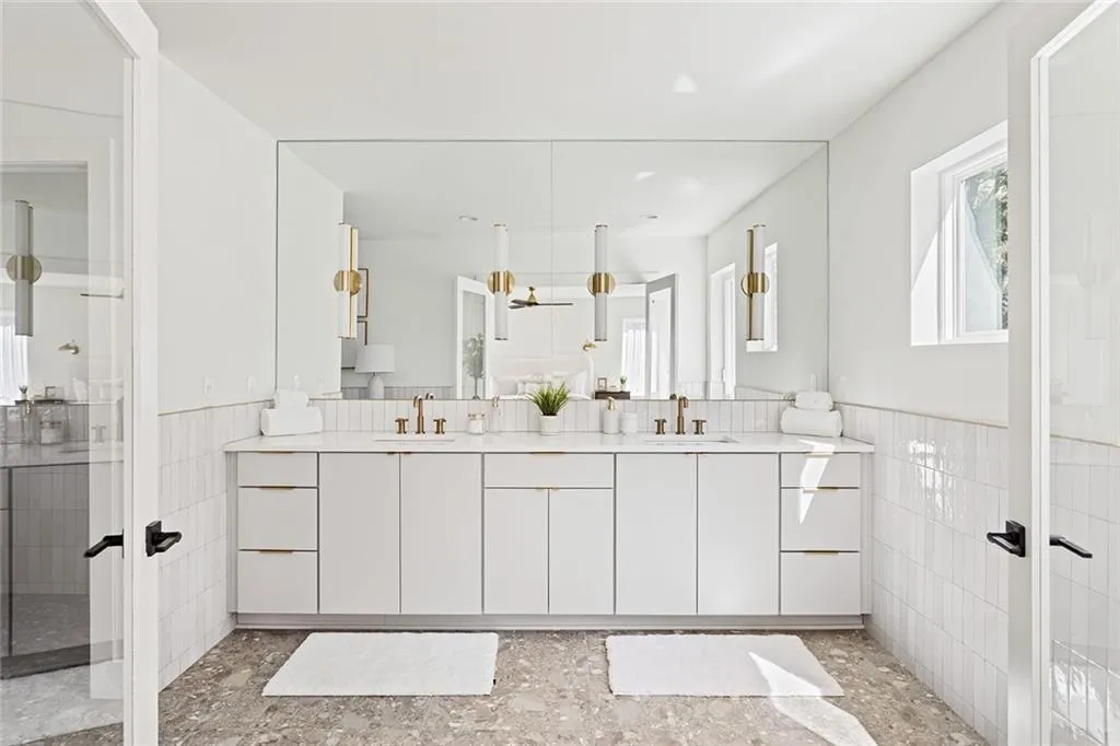 Bathroom with tile walls, a wainscoted wall, double vanity, plenty of natural light, and french doors
