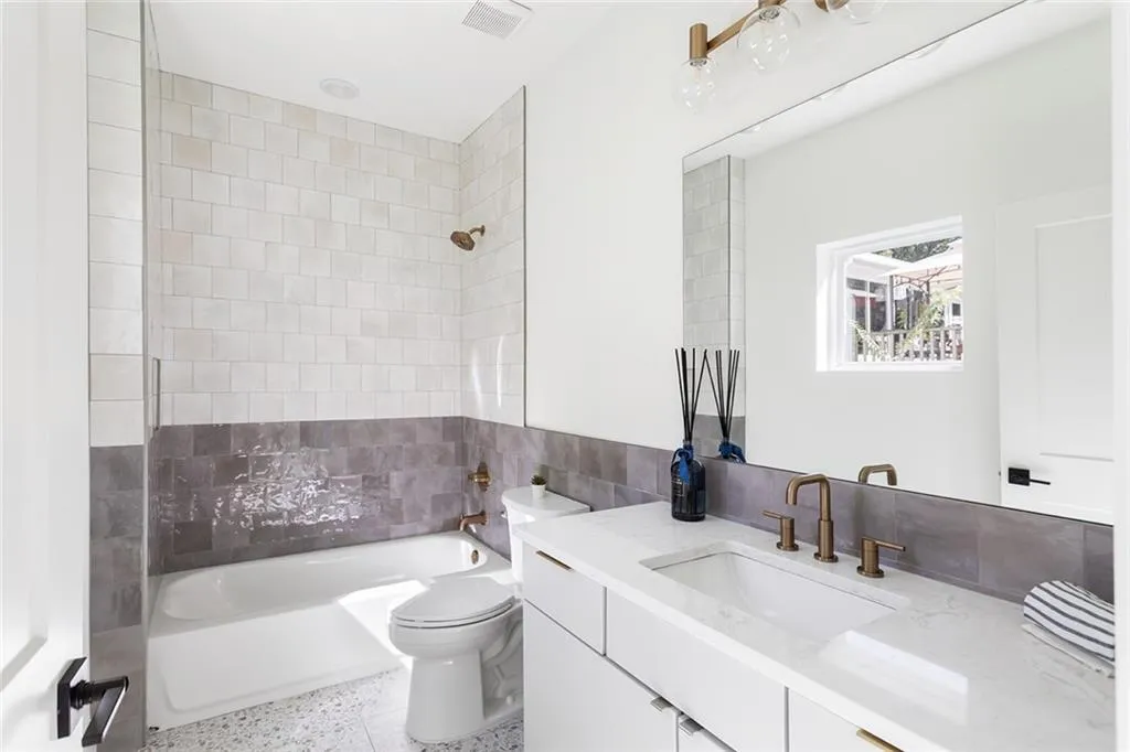 Bathroom with washtub / shower combination, vanity, tile walls, and dark speckled floor
