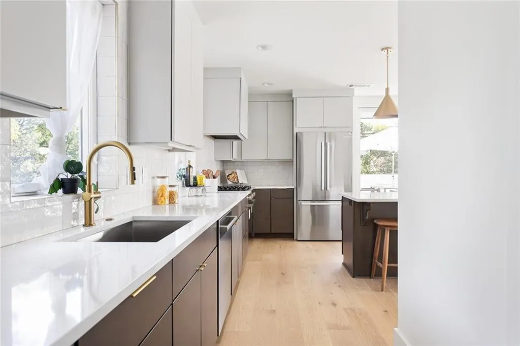 Kitchen featuring stainless steel appliances, modern cabinets, light wood-style floors, tasteful backsplash, and a breakfast bar area