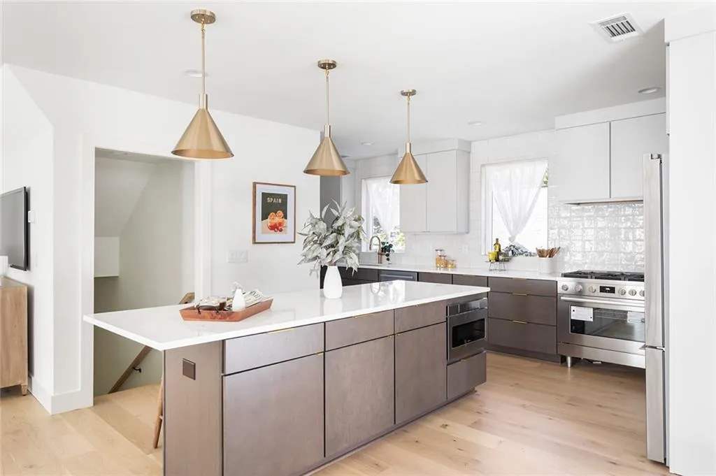 Kitchen featuring stainless steel appliances, tasteful backsplash, light wood-style flooring, white cabinets, and pendant lighting