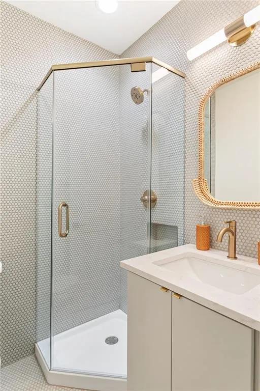 Full bath with vanity, a stall shower, and wallpapered walls