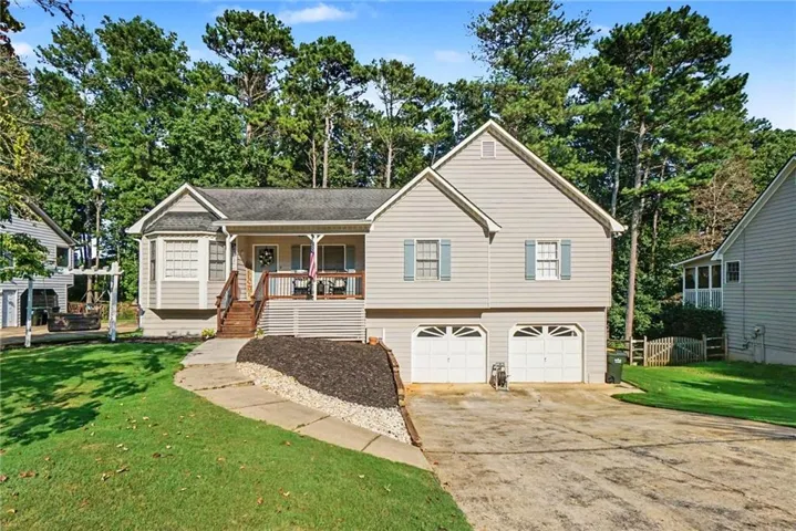 Siding exterior with a covered front porch, bay window, two-car garage, and established landscaping