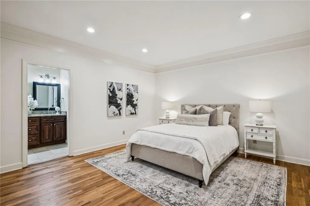 Bedroom featuring ornamental molding, wood finished floors, recessed lighting, and connected bathroom