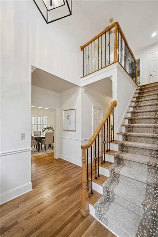 Stairs featuring a towering ceiling and wood finished floors