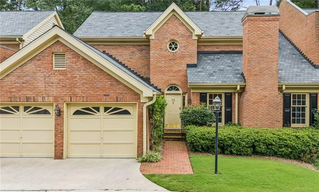 View of front of property with driveway, brick siding, a chimney, a front lawn, and a high end roof