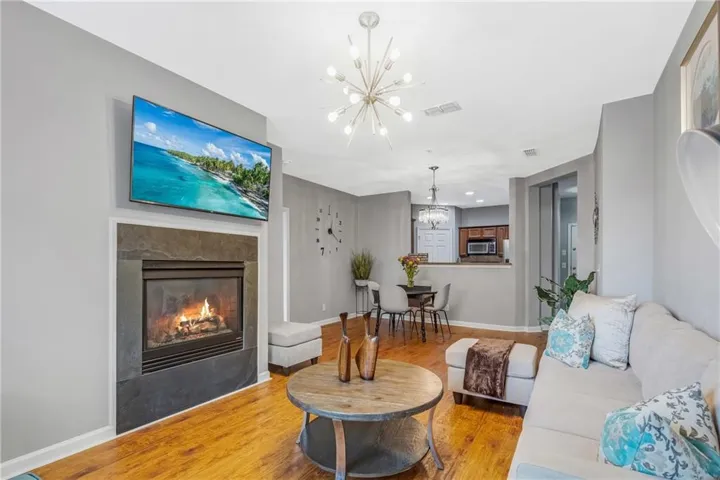 Living area with a slate-surround fireplace, hardwood flooring, and a contemporary chandelier