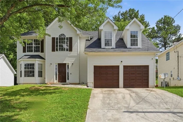 Two-story residence featuring white siding, brown front door, and a two-car garage with brown doors