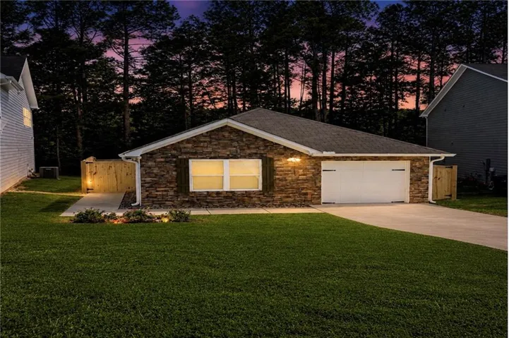 Stone veneer facade with an attached single-car garage and concrete driveway