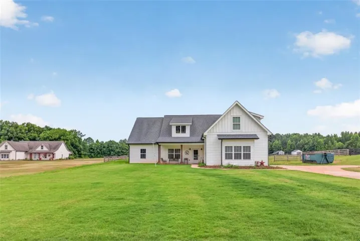 White farmhouse-style residence with a dark shingle roof and a covered front porch featuring columns