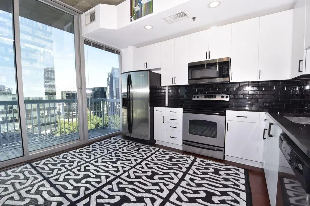 Kitchen (view to balcony) with stainless steel appliances (newer stove and microwave), granite counters, upgraded cabinets, hardware, lighting and faucet.