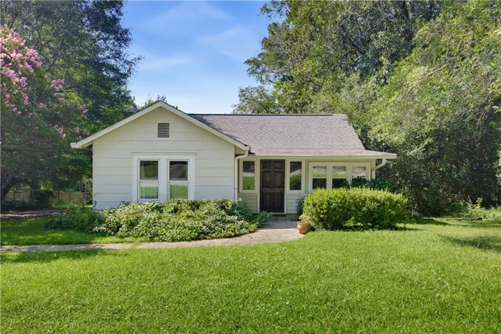 Light-colored siding exterior with a dark-stained entry door and a covered front porch featuring multiple windows