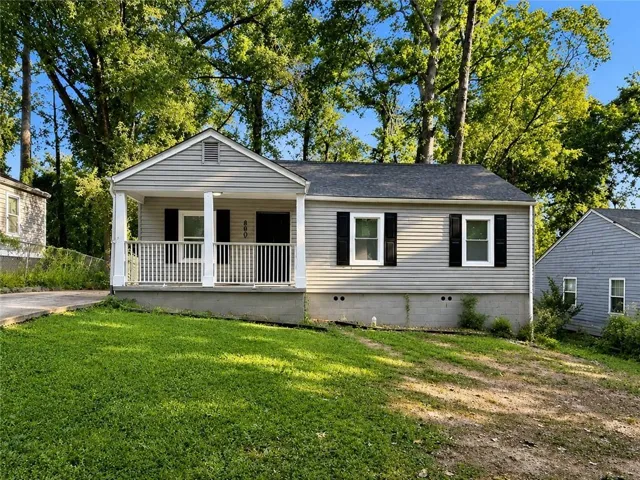 Gray siding exterior with white trim, covered front porch, white porch railing, and black window shutters