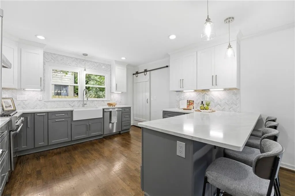 Updated kitchen with clean cabinetry, quartz countertops, and a large L-shaped breakfast bar with seating. A full Thermador appliance package, including a built-in refrigerator, adds a high-end, integrated feel, while under-cabinet lighting enhances both function and ambiance.
