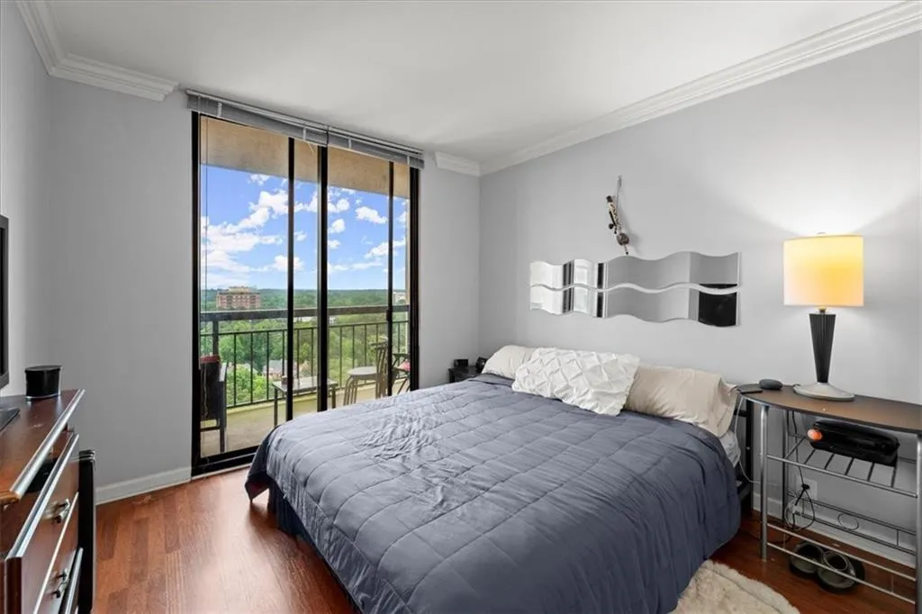 Bedroom with crown molding, wood finished floors, expansive windows, and access to exterior