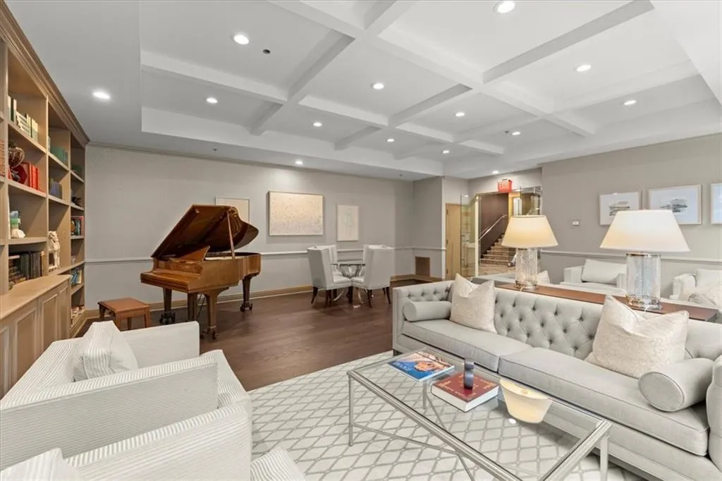 Living room with beam ceiling, coffered ceiling, wood finished floors, recessed lighting, and stairs
