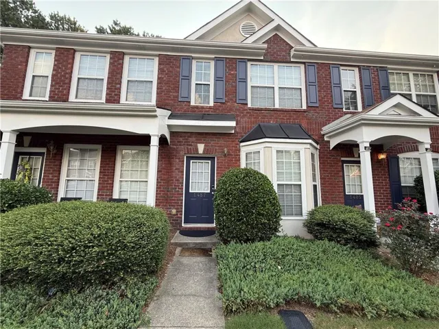 Brick facade townhouse with a covered entryway, bay window feature, and white window frames