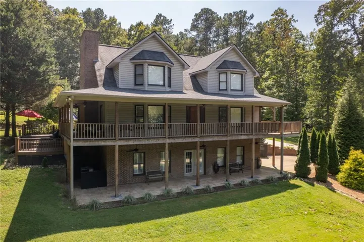 Two-story residence with a covered upper-level deck, a lower-level covered patio, and a wood deck with railings