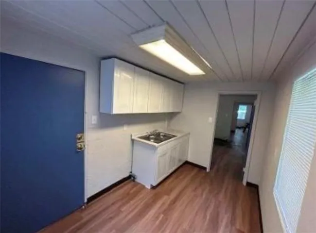 Kitchen featuring hardwood / wood-style floors, white cabinets, and sink