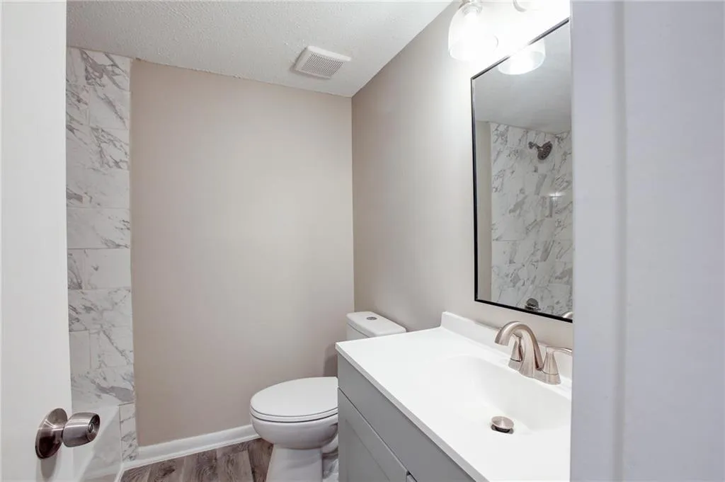 Full bath featuring vanity, wood finished floors, a shower, and a textured ceiling