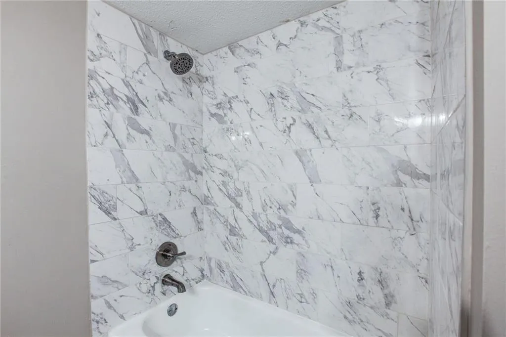 Bathroom featuring shower / bath combination and a textured ceiling
