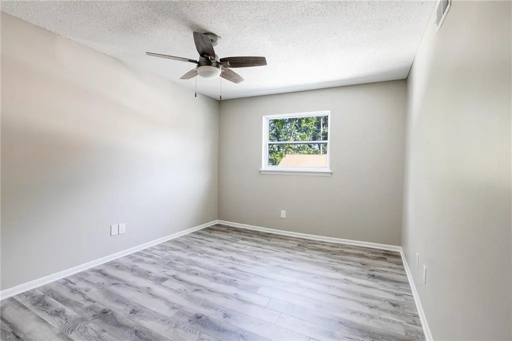 Empty room with wood finished floors, a textured ceiling, and a ceiling fan