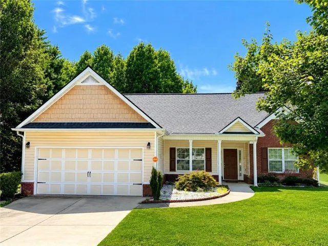 Siding exterior with brick accents, covered front entry, attached garage, and a concrete driveway