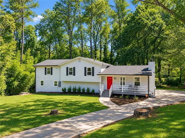 Split-level residence featuring a red entry door, covered porch, and white railings