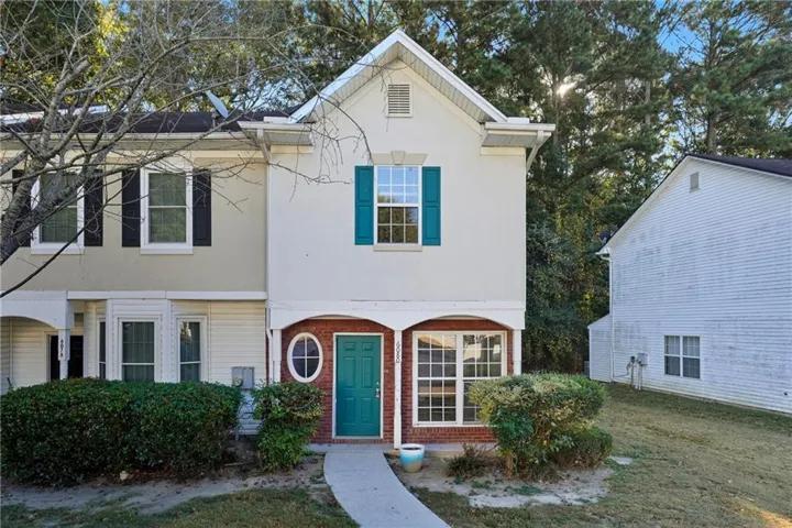 Charming two-story home featuring a cream exterior with teal-trimmed shutters and matching entry door