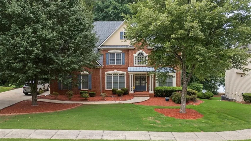 Traditional brick residence featuring a prominent front entrance with a covered porch