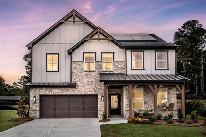 Modern farmhouse with roof mounted solar panels, board and batten siding, a standing seam roof, a front lawn, and a garage