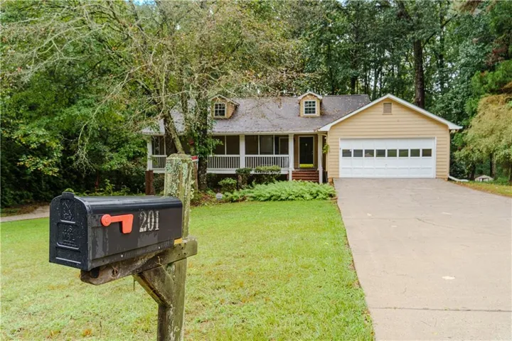 Single-story residence featuring a covered front porch, attached garage with white paneled door, and a dormer window