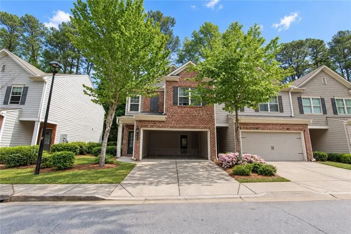 Brick and siding facade with attached garage, concrete driveway, and mature landscaping