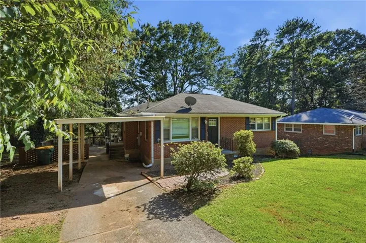 Brick exterior with a dark-shingled roof, featuring a covered carport and a manicured front lawn