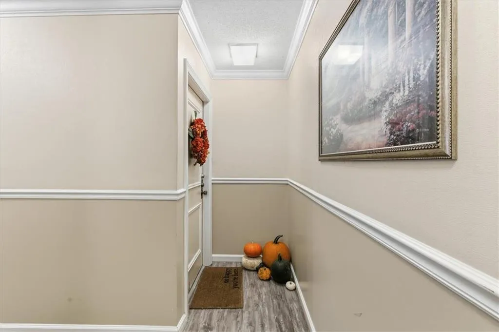 Doorway to outside featuring ornamental molding, wood finished floors, and a textured ceiling