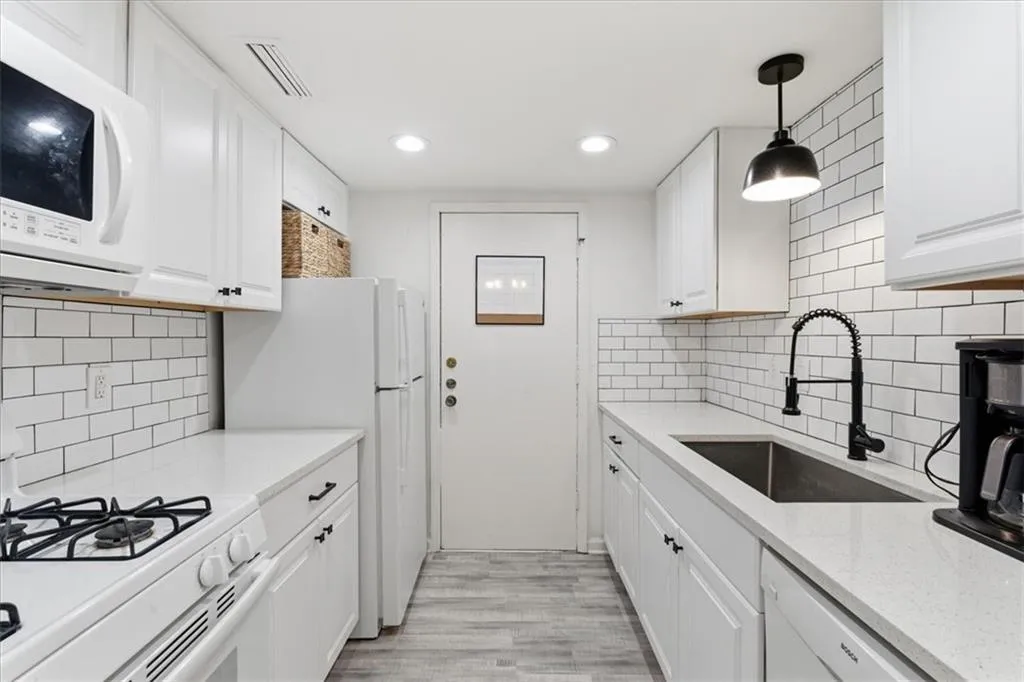 Kitchen featuring hanging light fixtures, white cabinetry, white appliances, light stone countertops, and recessed lighting