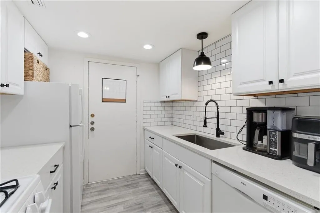 Kitchen with white cabinets, decorative light fixtures, white appliances, and recessed lighting