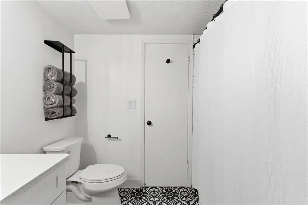 Bathroom featuring a textured ceiling, a shower with shower curtain, vanity, and tile patterned floors