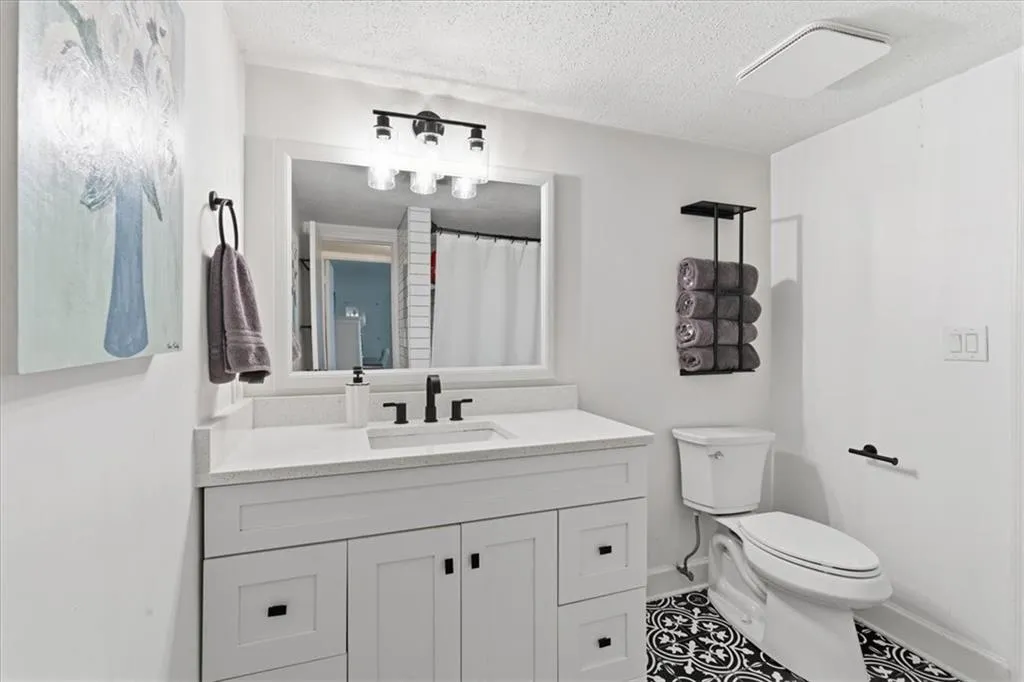 Bathroom with vanity, a shower with shower curtain, a textured ceiling, and tile patterned floors
