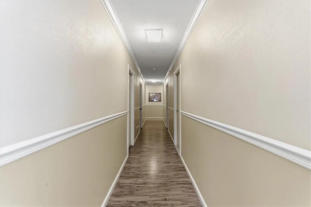 Corridor with ornamental molding, dark wood finished floors, and a textured ceiling