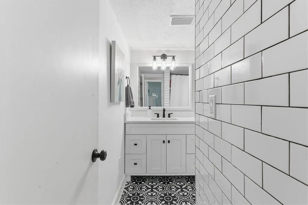Bathroom with a textured ceiling, vanity, tile patterned flooring, and a shower with shower curtain
