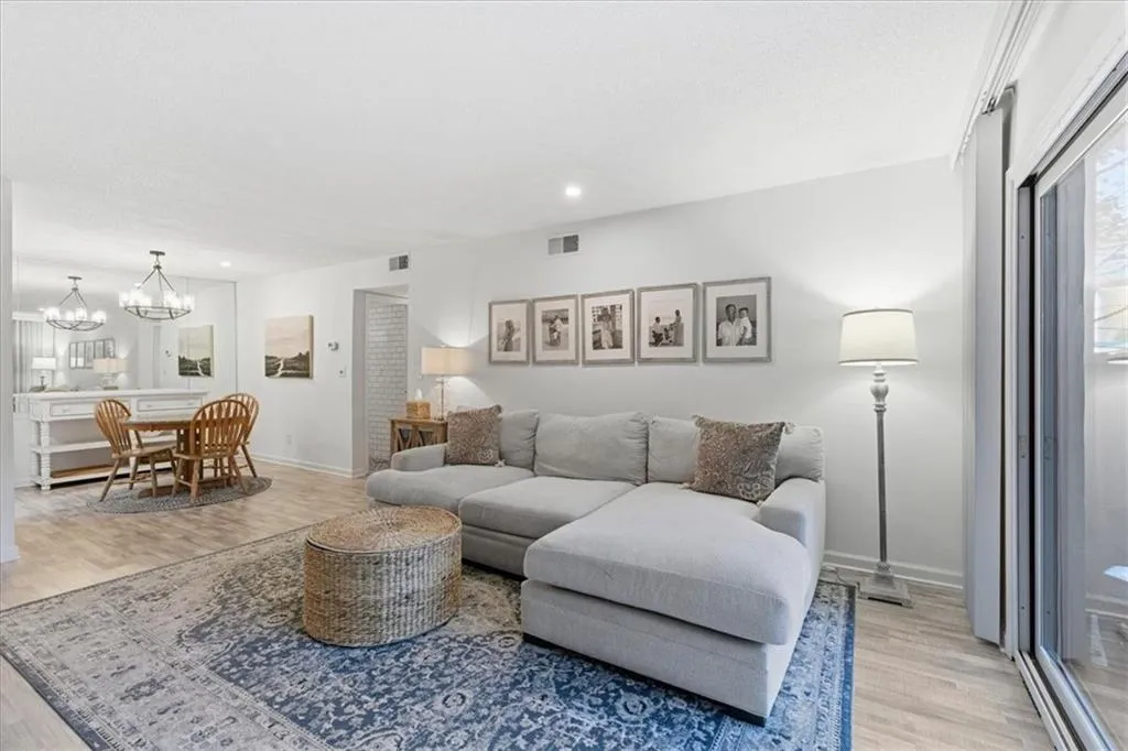 Living room with light wood-type flooring, recessed lighting, healthy amount of natural light, and a chandelier