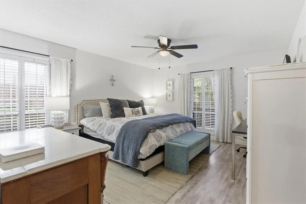 Bedroom featuring light wood-style flooring, a ceiling fan, a textured ceiling, and an office area